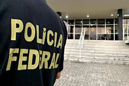 Imagem colorida mostra parte do colete de um agente da Polícia Federal