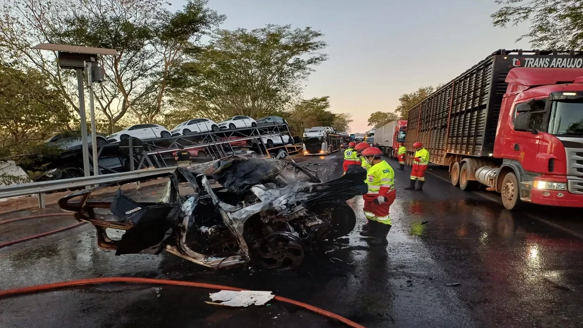 Imagem colorida mostra um carro totalmente destruído em uma rodovia após um acidente.