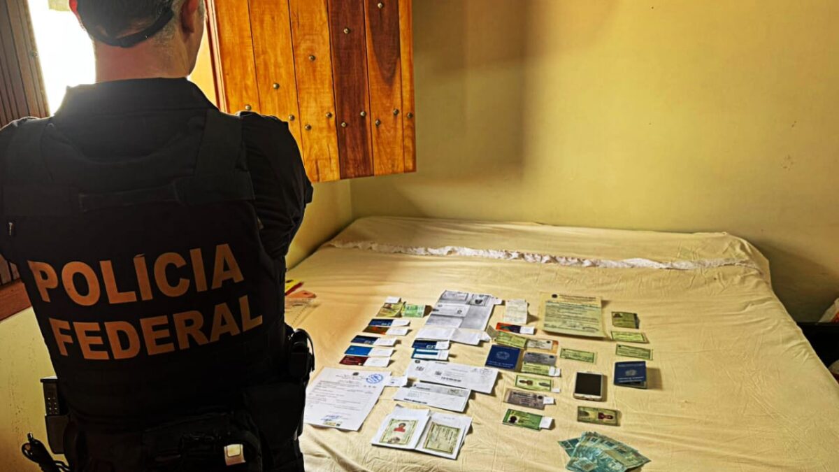 Imagem mostra um agente da policia de costas olhando para uma cama cheia de documentos