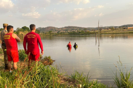 Imagem mostra dois militares do Corpo de Bombeiros dentro de um lago realizando um trabalho de resgate.