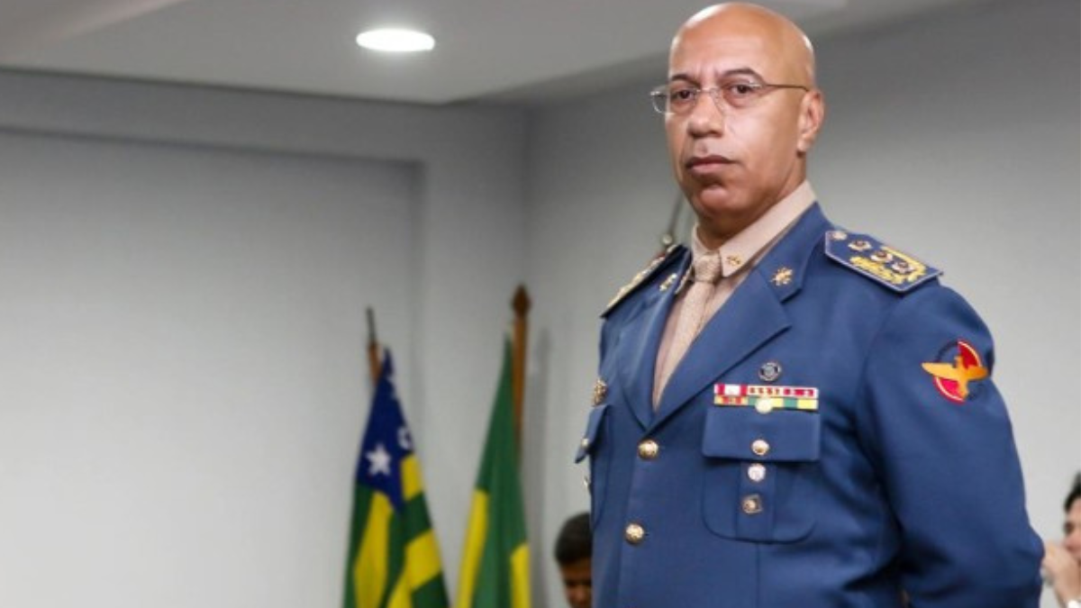 Imagem colorida mostra o ex-subcomandante do Corpo de Bombeiros Militar de Goiás (CBMGO), Divino Aparecido em pé com as bandeiras de Goiás e do Brasil ao fundo.
