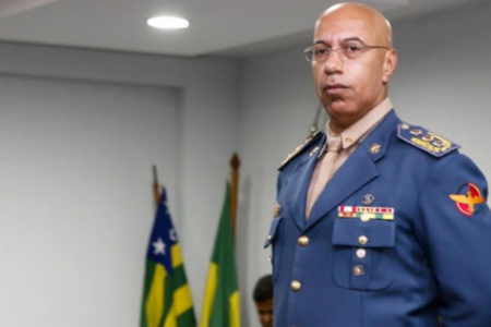 Imagem colorida mostra o ex-subcomandante do Corpo de Bombeiros Militar de Goiás (CBMGO), Divino Aparecido em pé com as bandeiras de Goiás e do Brasil ao fundo.