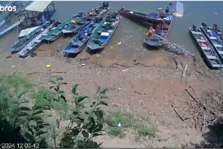 Foto mostra barcos parados nas margens de rum rio