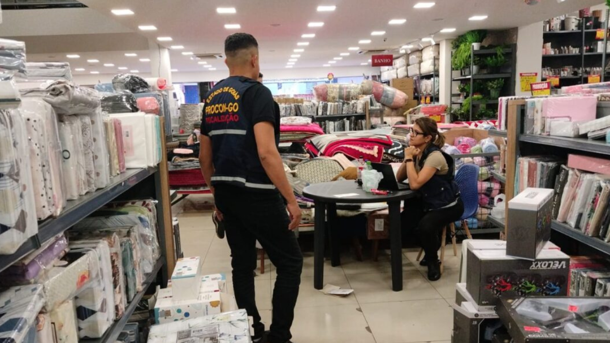 Imagem colorida mostra um agente do Procon Goiás e uma loja de enxovais