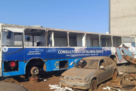 A imagem mostra um ônibus azul e um carro cinza como se estivessem abandonados