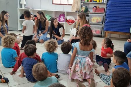 Imagem mostra uma sala de aula com professores e crianças