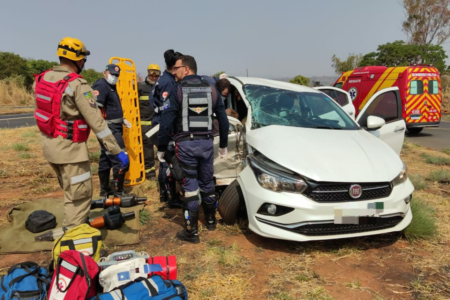 Imagem colorida mostra médicos do SAMU trabalhando ao lado de um carro branco após um acidente