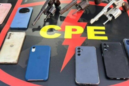 Imagem colorida mostra diversos celulares em cima do capô de uma viatura da Polícia.