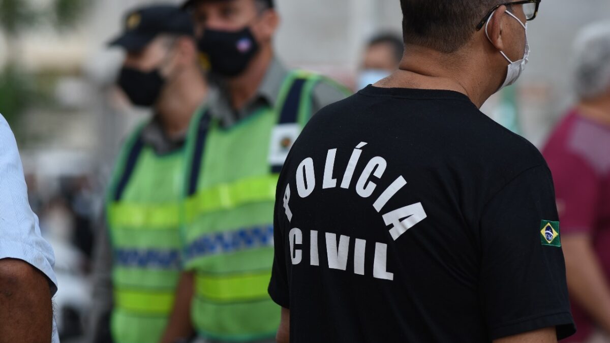 A imagem mostra dois policiais militares e um policial civil