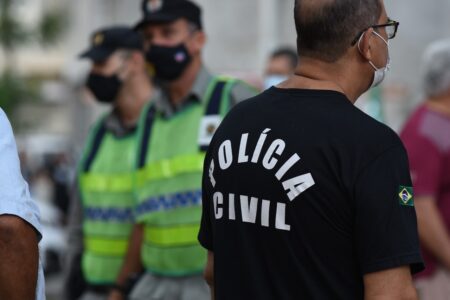 A imagem mostra dois policiais militares e um policial civil