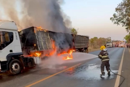 Imagem colorida mostra um Bombeiro Militar apagando o fogo que atingiu uma carreta em uma rodovia.