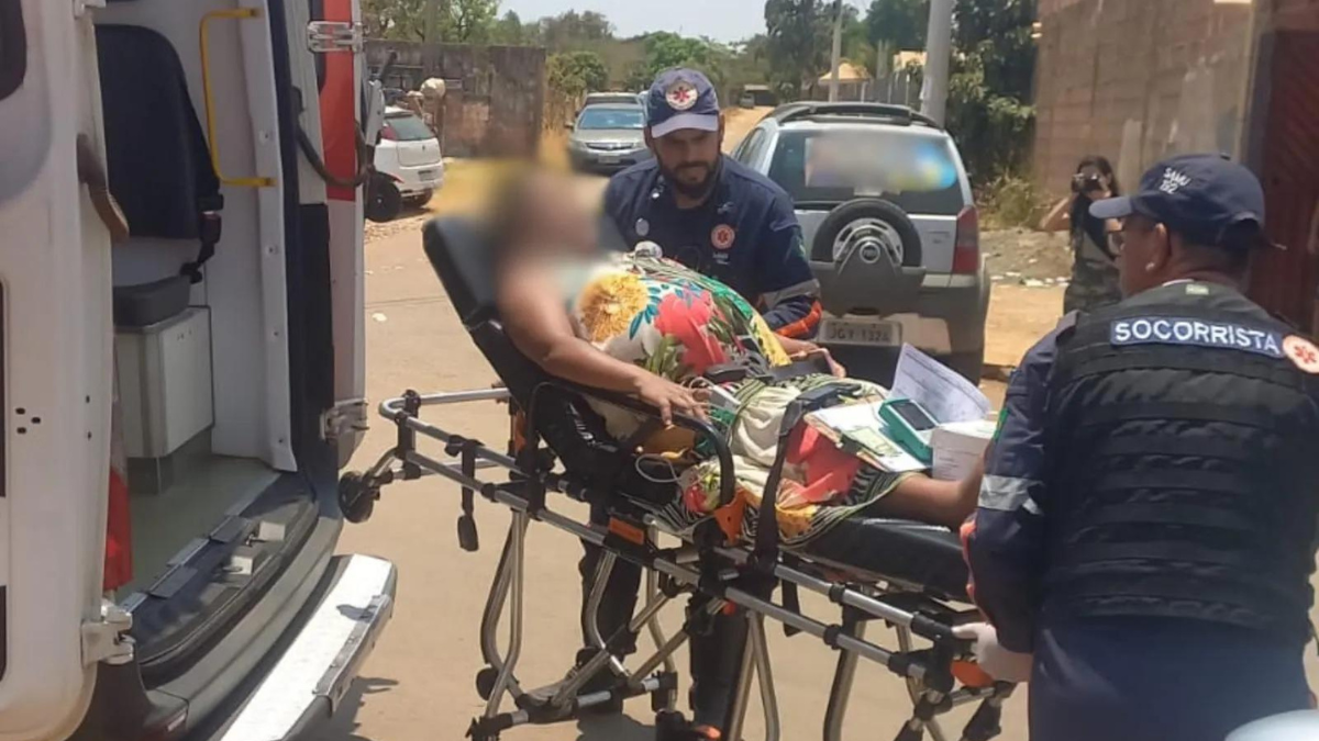 Imagem colorida mostra uma mulher grávida, usando um vestido colorido, em cima de uma maca.
