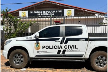 Imagem mostra a fachada de uma delegacia com um carro na frente