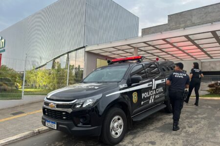 Imagem mostra fachada de um hospital e uma viatura preta da policia parada em frente