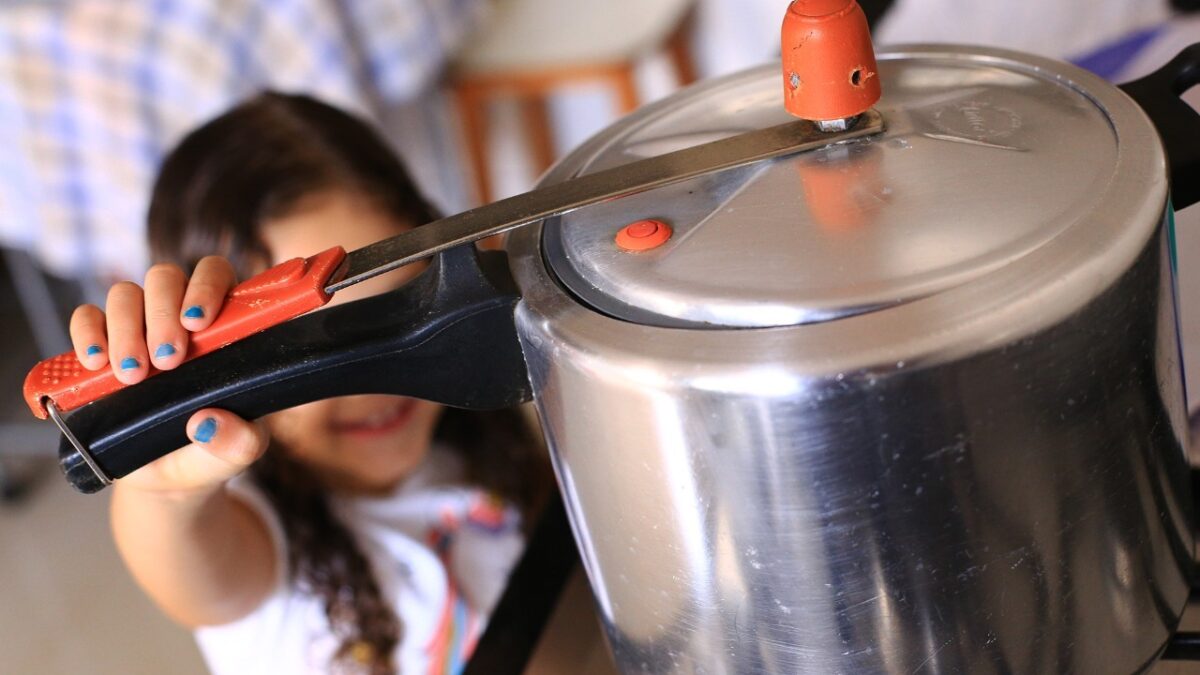 Criança alcança uma panela que está no fogão