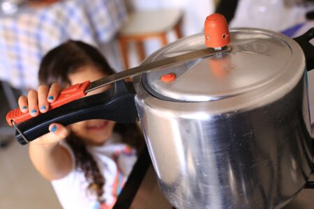 Criança alcança uma panela que está no fogão