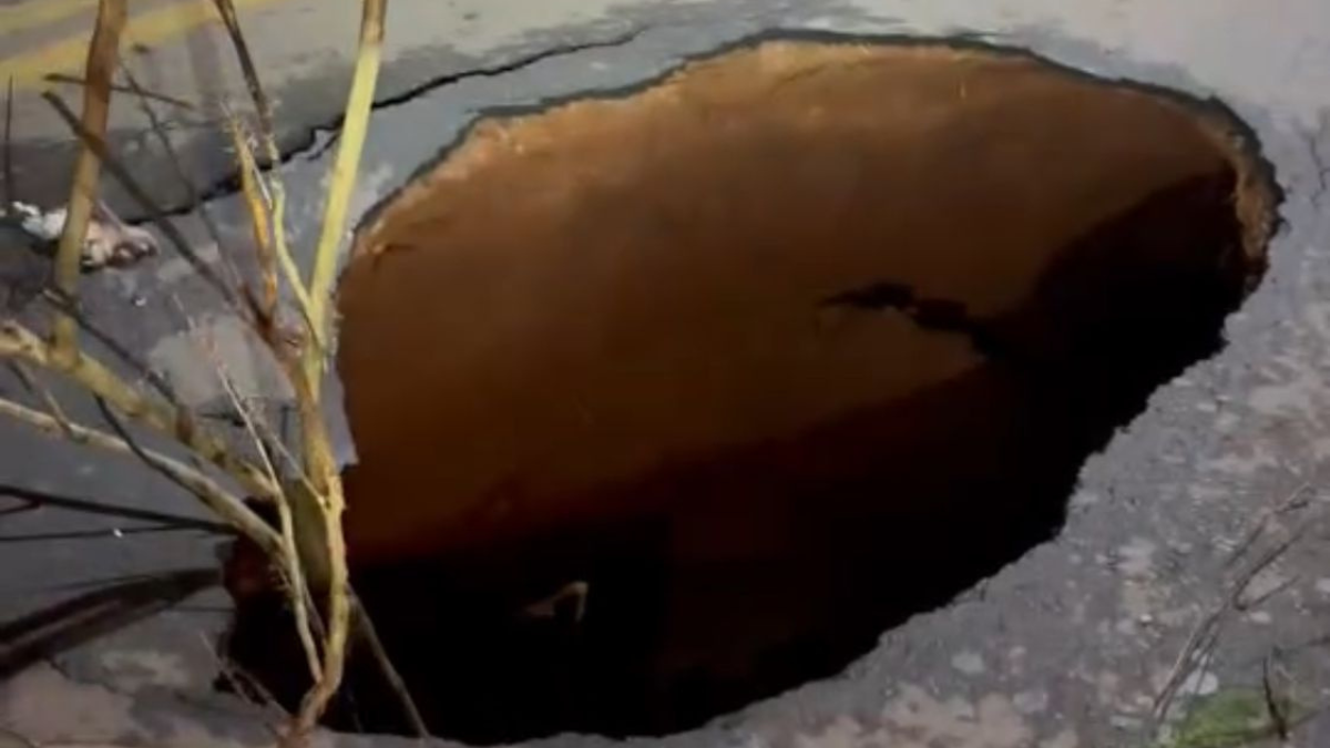 Imagem colorida mostra uma cratera que foi aberta em uma rua de Goiânia.