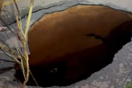 Imagem colorida mostra uma cratera que foi aberta em uma rua de Goiânia.