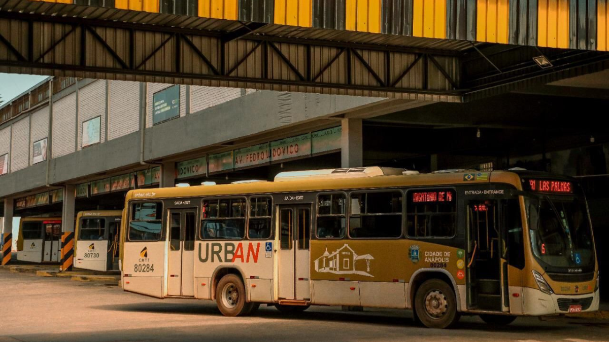Imagem colorida mostra um ônibus do transporte coletivo parado em um terminal de ônibus.