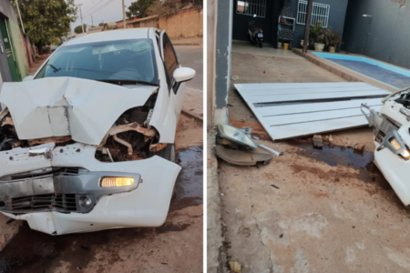 Imagem colorida mostra um carro branco com a frente estragada após bater em um portão que aparece caído do lado direito.