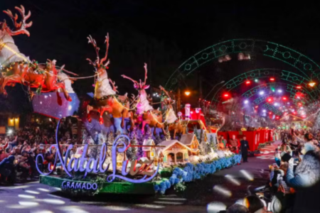 Imagem do grande desfile de natal em Gramado, com renas no trenó e luzes coloridas