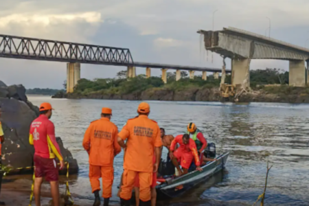 Bombeiros resgatando uma pessoa de bote, ao longe mostra parte da estrutura que não desabou