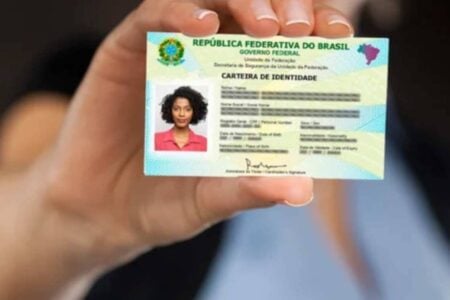 Mão de mulher segura nova Carteira de Identificação Nacional (CIN)