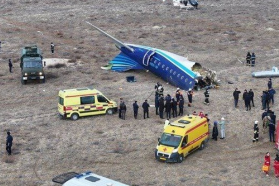 Imagem da calda do avião repartida e agentes no local