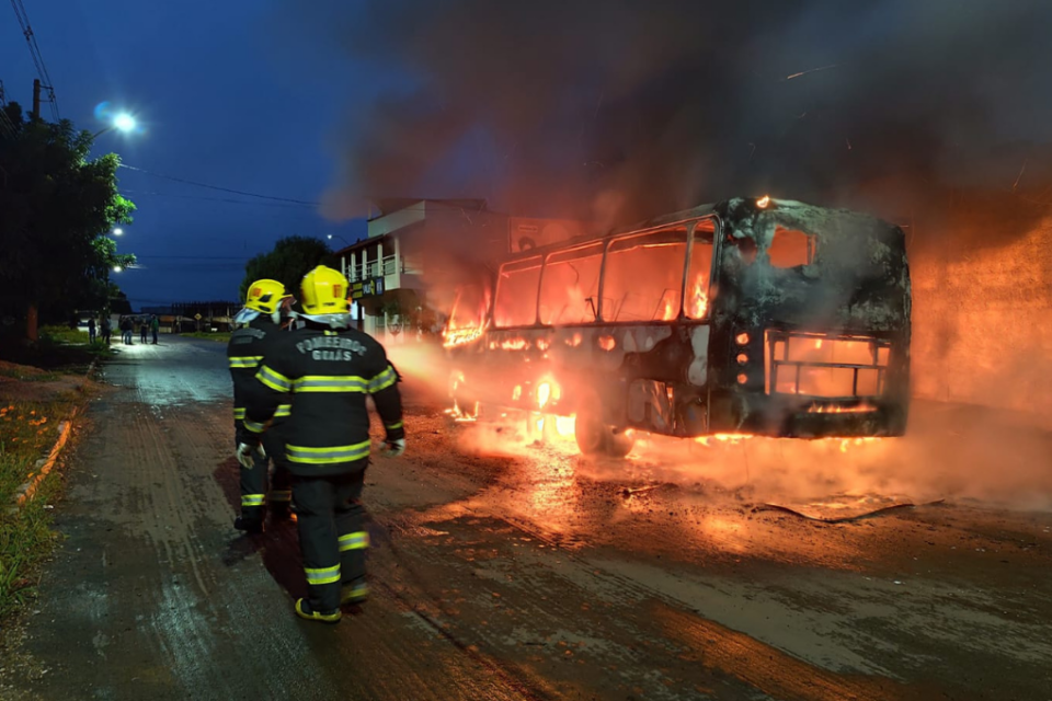 Imagem colorida mostra militares dos bombeiros combatendo um incêndio que atinge um micro-ônibus.