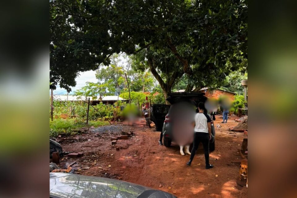 A imagem mostra um homem sendo preso por um policial civil em uma área rural