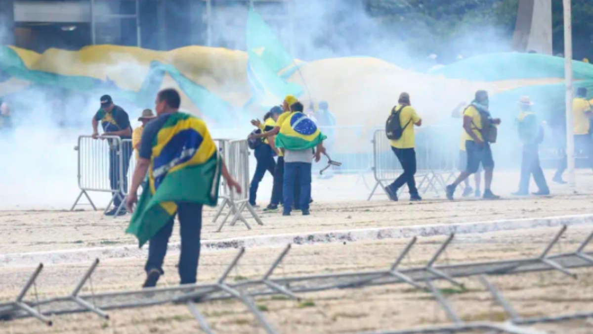 Imagem dos participantes do ataque em 08/01 correndo em meio à fumaça