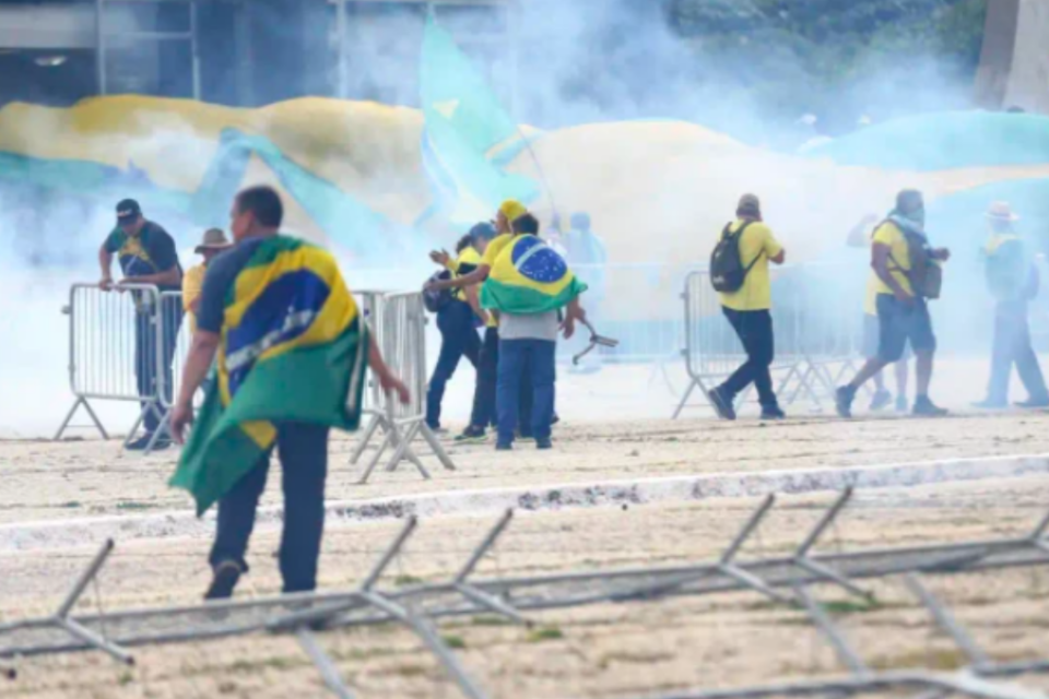 Imagem dos participantes do ataque em 08/01 correndo em meio à fumaça