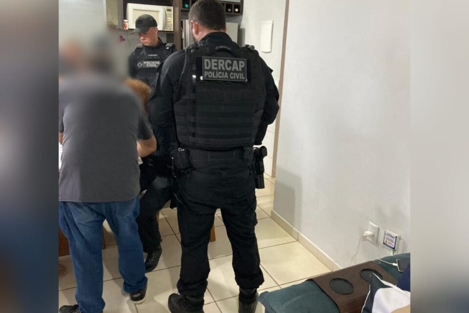 A imagem mostra a polícia cumprindo mandados em uma residência