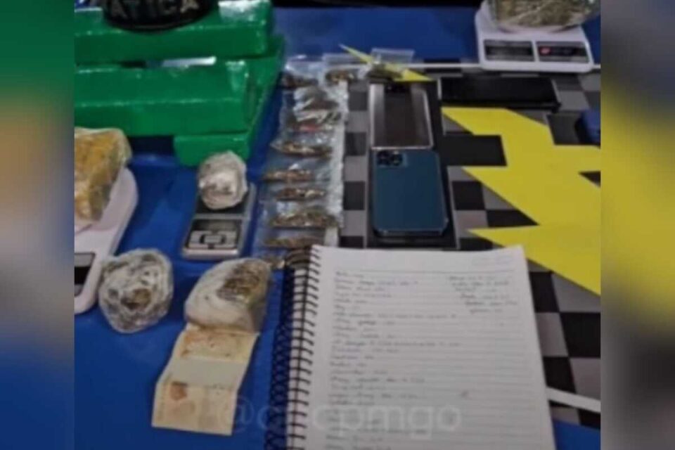A imagem mostra os itens apreendidos na residência abordada pela PM, Na imagem aparecem 10 kg de maconha, balança de precisão, aparelhos celulares e um caderno sobre o capô de uma viatura