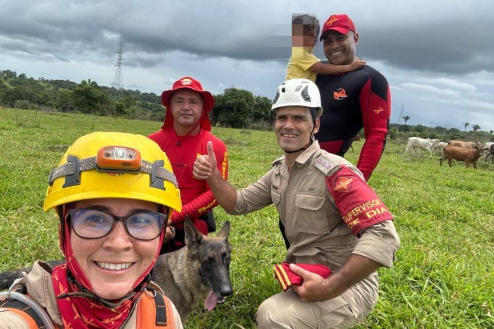 A imagem mostra a equipe de resgate com a criança, e a cadela Mera que ajudou nas buscas