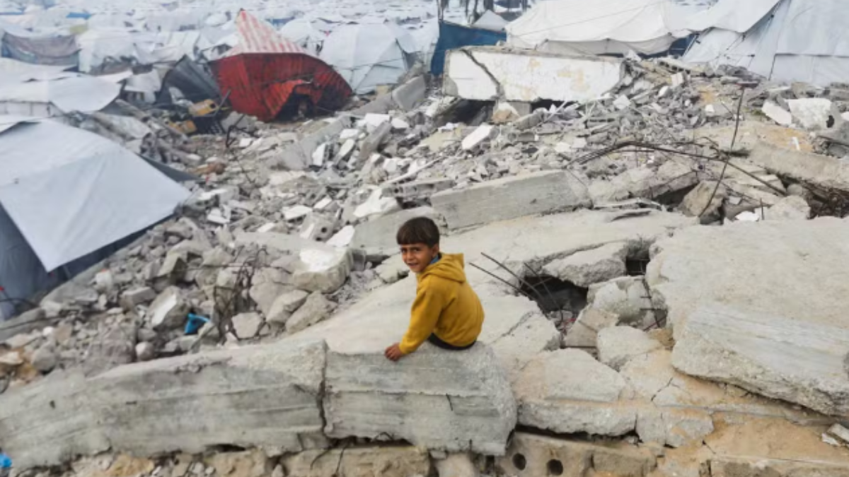 Menino senta em escombro perto de acampamento para refugiados na Cidade de Gaza