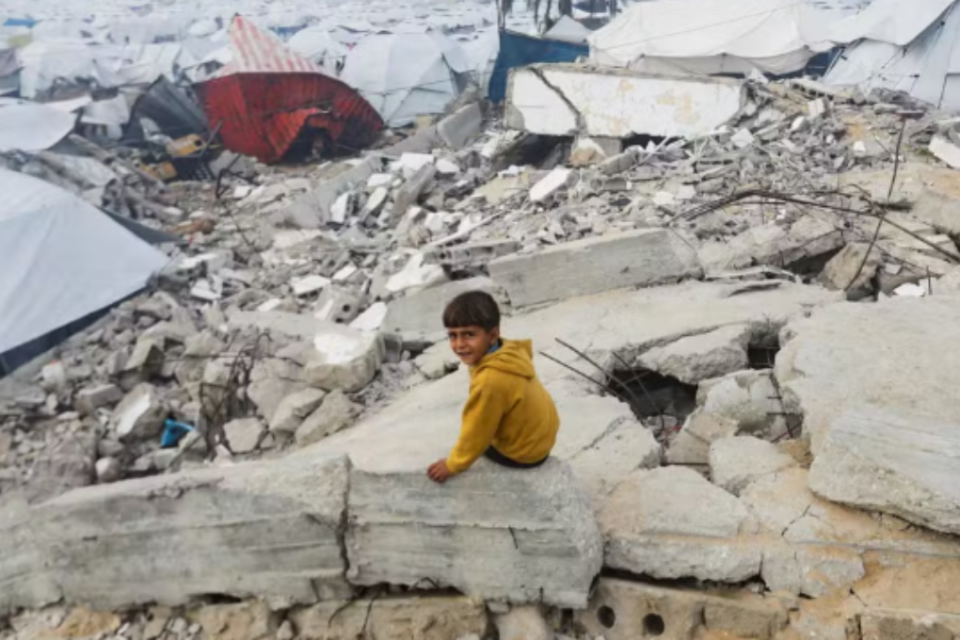 Menino senta em escombro perto de acampamento para refugiados na Cidade de Gaza
