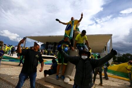 Bolsonaristas sobre estátua da deusa grega Têmis, na frente do STF, durante atos golpistas de 8 de janeiro (Foto: Agência Brasil)