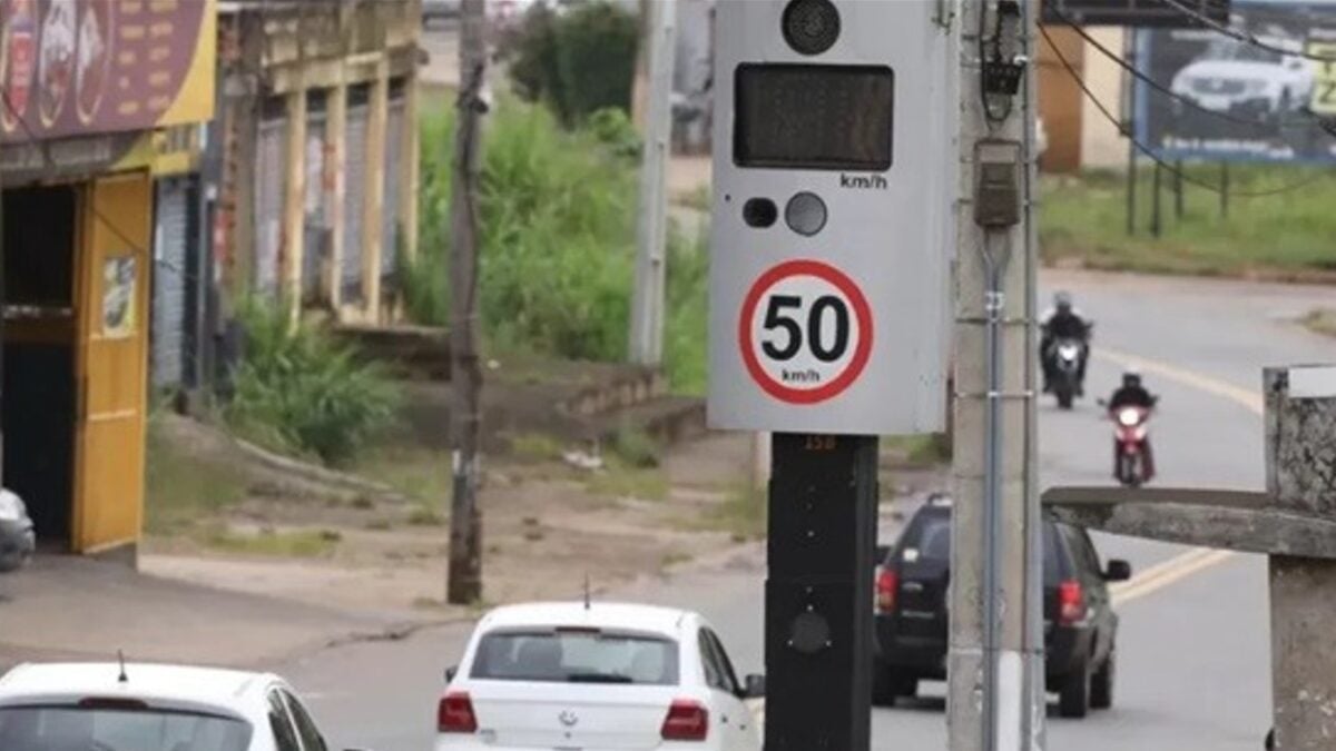 A imagem mostra o trânsito com vários carros descendo uma rua de Goiânia, com foto em um aparelho que fiscaliza a velocidade dos veículos