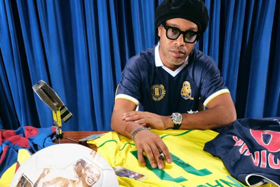 Ronaldinho Gaúcho autografando camisas e bola de futebol
