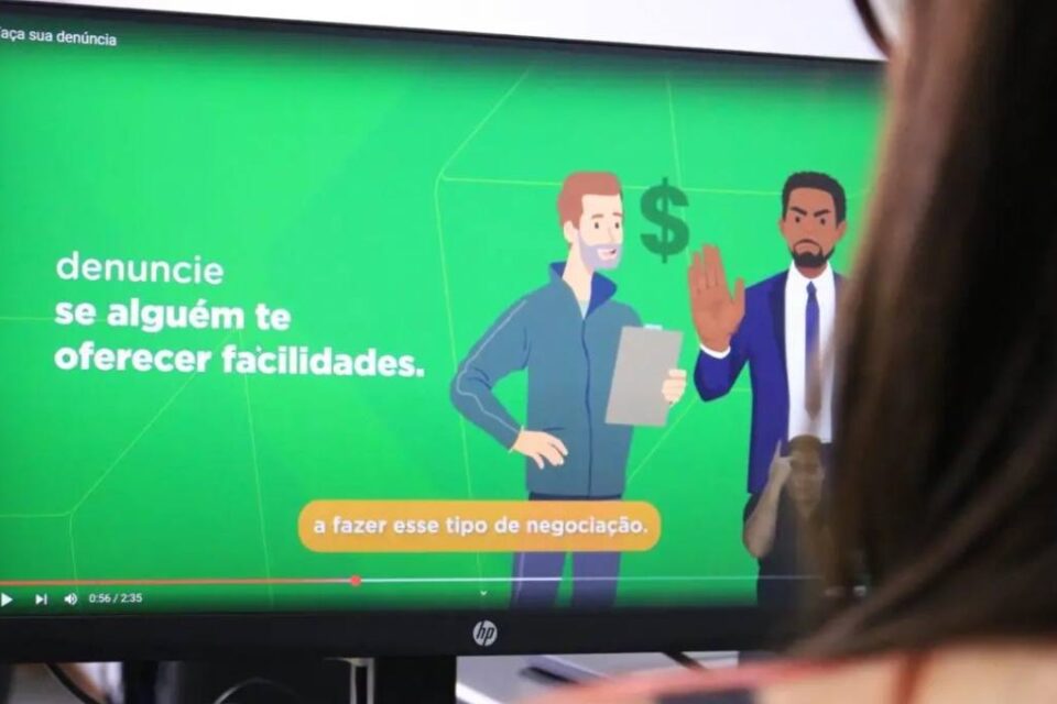 Imagem colorida mostra parte da cabeça de mulher virada para uma tela de computador.