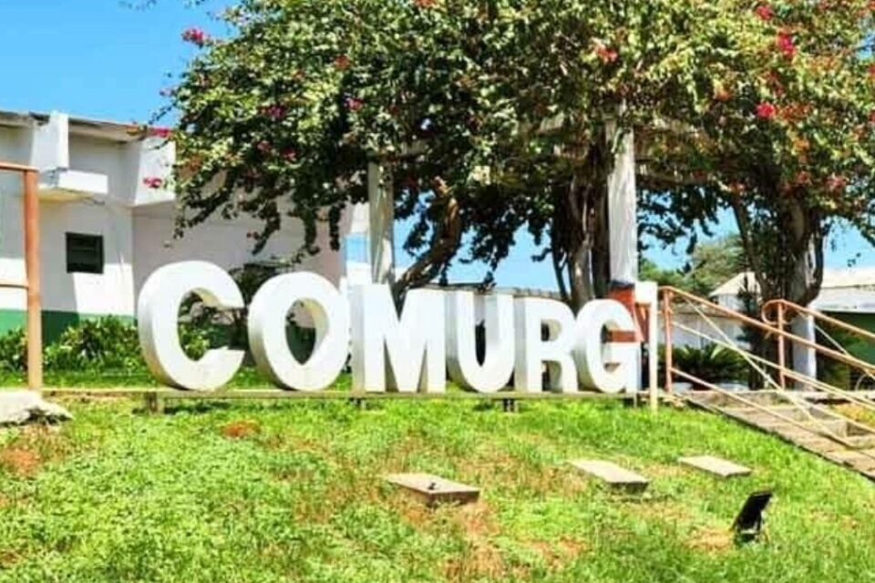 A imagem mostra o letreiro feito em cimento da Comurg em cima de um gramado, sinalizando a fachada da empresa