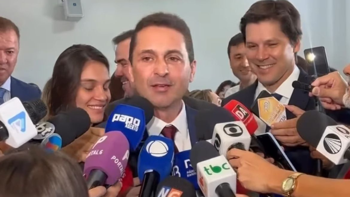 Imagem colorida mostra o prefeito eleito de Aparecida, Leandro Vilela, durante entrevista coletiva com diversos repórteres.