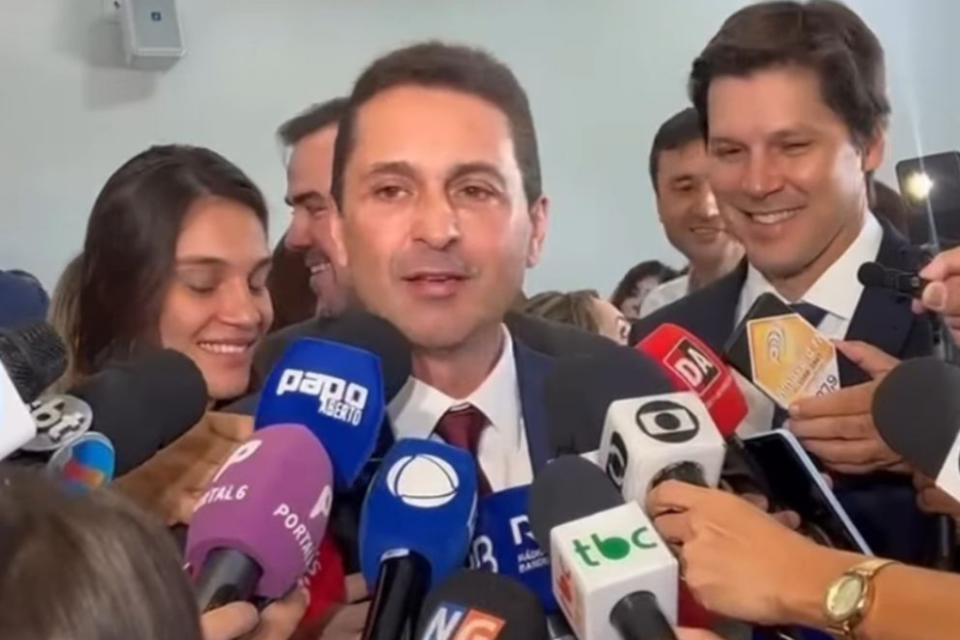 Imagem colorida mostra o prefeito eleito de Aparecida, Leandro Vilela, durante entrevista coletiva com diversos repórteres.