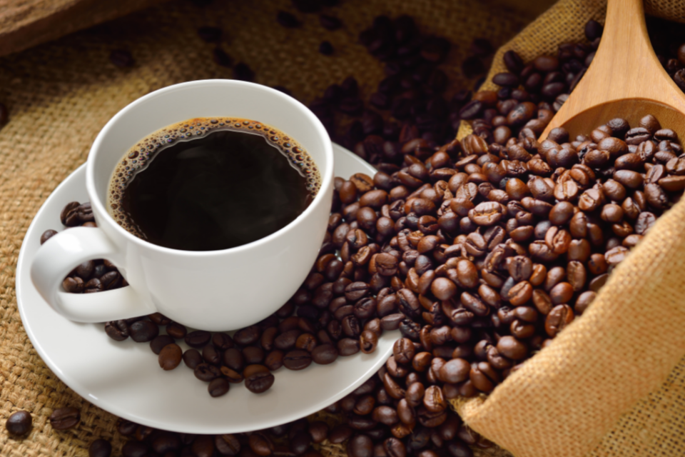 Imagem de uma xícara de café e grãos do café ao redor