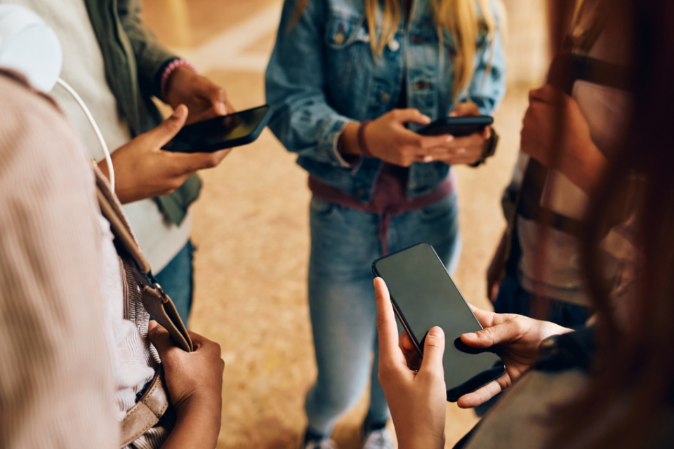 Imagem de adolescentes reunidos e usando celulares
