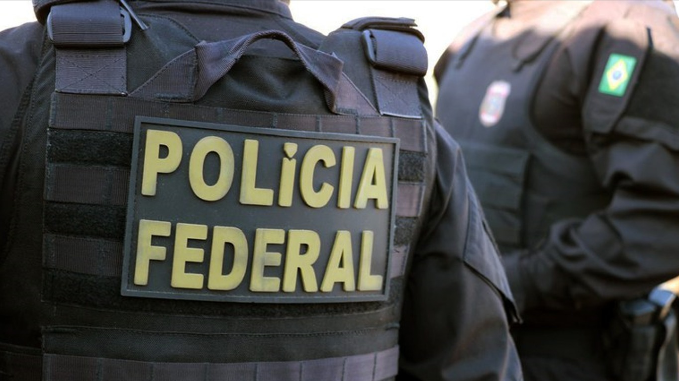 A imagem mosta o uniforme de um policial federal de costas