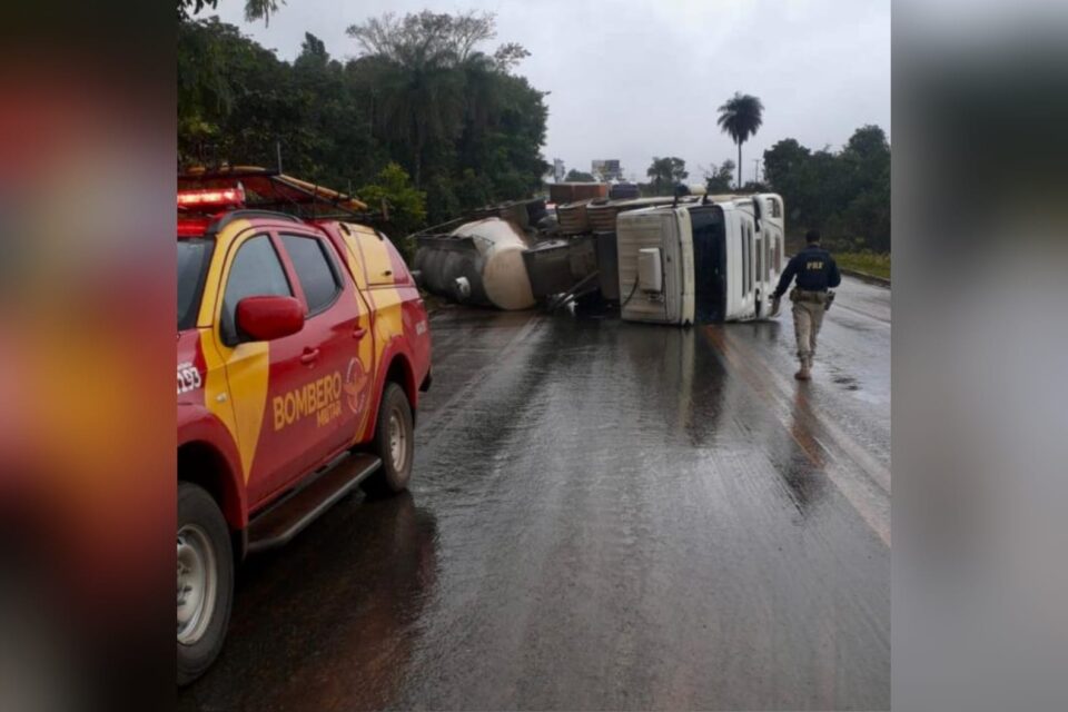 A foto mostra uma carreta tombada na pista e um carro do Corpo de Bombeiros a frente