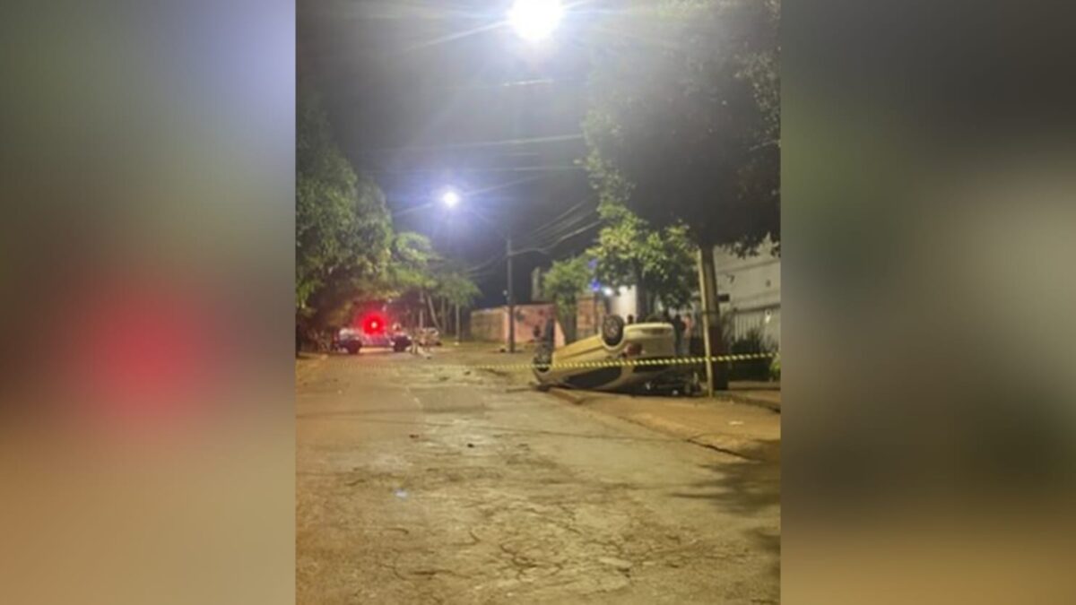 A imagem mostra o carro capotado sobre a motocicleta em cima de uma calçada