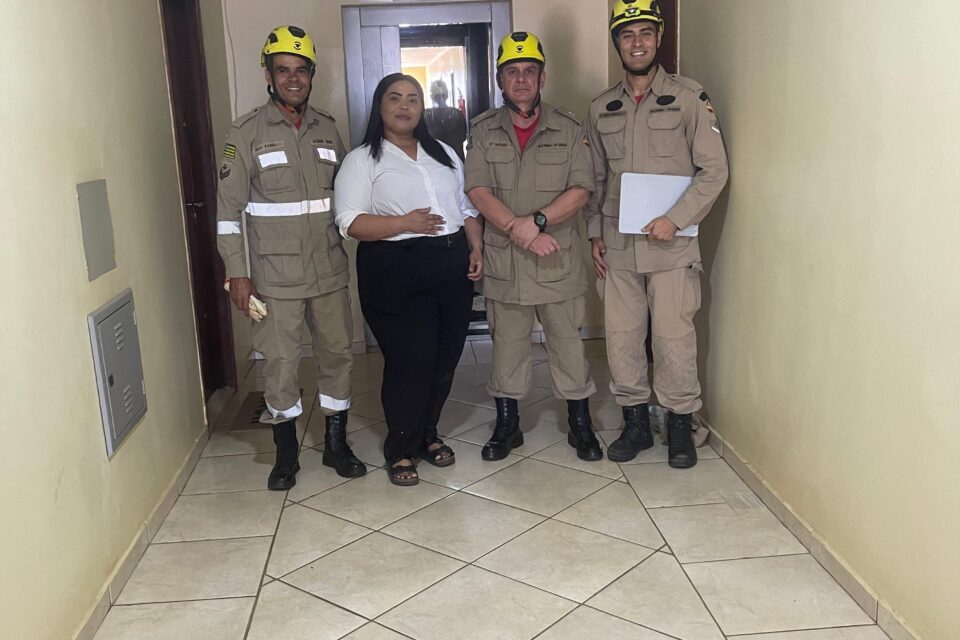 A imagem mostra a vítima juntamente com a equipe de resgate do Corpo de Bombeiros que a tirou do elevador